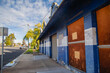 © Austockphoto - Abandoned blue and white brick building with boarded-up windows on a sunny day