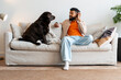© Maria Vitkovska - Man and dog sharing a relaxing moment on sofa while listening to music