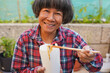 © Sabrina - Happy senior asian woman eating instant noodles during lunch break outdoor - Fast food, culture and elderly person lifestyle concept