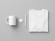 © OrnaArt - A neatly arranged still life of a folded white t-shirt, coffee mug, notebook, and pen on a gray surface.