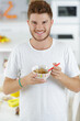 © auremar - good looking young man eating cereal and smiling in kitchen
