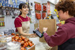 © ADDICTIVE STOCK - Shop assistant smiling at checkout counter in fruit store