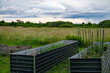 © .shock - Raised garden beds in a rural meadow near a modern modular home promoting low energy and sustainable living with solar panels