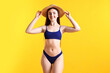 © New Africa - Beautiful young woman wearing stylish blue bikini and straw hat on yellow background