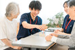 © buritora - A senior citizen and a male and female occupational therapist using cylinder pegs for hand function training during rehabilitation.
