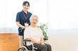 © buritora - A senior woman in a wheelchair and a female staff member working at a nursing home.