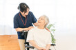 © buritora - A senior woman in a wheelchair and a female staff member working at a nursing home.