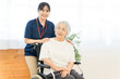 © buritora - A senior woman in a wheelchair and a female staff member working at a nursing home.