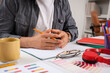 © Pixel-Shot - Young businessman with color palettes, cup of coffee and notebook on table at office, closeup