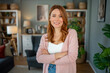 © Jelena - Confident red-haired woman smiling with crossed arms
