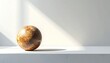 © Ikhsan - Sphere with mottled surface sits on a white shelf, shadow cast across wall