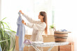 © Pixel-Shot - Young woman with clean shirt in laundry room