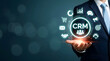 © MJ STUDIO - Businessman holding glowing CRM hologram with related business marketing and customer relationship management icons