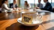 © Fatimazahra7788356 - Coffee cup with break time text on table in office meeting background with business people blur