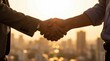 © Olivia - Two individuals shaking hands against a blurred city skyline at golden hour, symbolizing agreement.