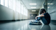 © Маргарита Пархоменко - Sad young boy sitting alone in a school hallway with backpack