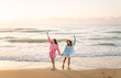 © maxbelchenko - Two friends are having fun on the beach on a sunny day. Beautiful friends are spending time together, enjoying the seascape at sunset. Concept of friendship, nature, and vacation.