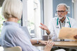 © Westend61 - Doctor consulting patient with documents and notebook in office
