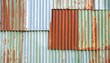 © Cici - Close-up on a textured surface showing various panels. The corrugated sheets display rust and wear. A mix of colours with metallic base
