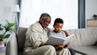 © Mary - Senior man reading a book with young boy on sofa in cozy living room.