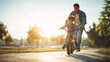 © KotBaton - Father teaching his son to ride a bicycle at sunset in park. Family bonding, childhood learning and happy lifestyle concept.