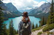 © Vadym - Young woman with backpack and headphones stands on mountain path. She overlooks turquoise lake forest valley and peaks. Clouds fill sky above scenic landscape.
