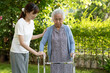 © amazing studio - Caregiver help Asian elderly woman patient walk with walker in park, healthy strong medical concept.