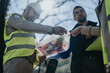 © qunica.com - Construction engineers examine a rolled blueprint together at an outdoor job site. The team discusses project plans and site details while wearing safety gear.