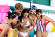 © Xavier Lorenzo - Diverse young friends laughing and sharing happy moments, viewing content together on a mobile phone during a summer beach vacation, holding a beach ball and snorkeling gear