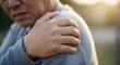 © designhunt - Middle aged man suffering from acute shoulder pain. Lifestyle health issues and muscle tension. Man holding his painful shoulder outdoors with a facial expression of discomfort