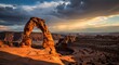 © Aura - Majestic natural rock arch standing against a dramatic sunset sky with sweeping clouds and golden light over a canyon landscape