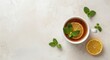 ©  AugmentArt - Top view of white cup holding healthy ginger tea with lemon slice and mint leaves on an unadorned background with copy space
