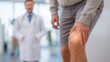 © TensorSpark - Patient holding knee in clinic with doctor in background, representing trauma rehabilitation and injury pain management.