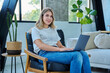 © Valerii Honcharuk - Portrait of young woman sitting on chair with laptop, in home interior