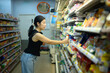 © Prathankarnpap - Woman choosing yogurt from refrigerated shelf in supermarket