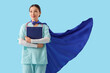 © Pixel-Shot - Female Asian doctor with superhero cape and clipboard on blue background. International Nurses Day