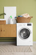 © Pixel-Shot - Interior of laundry room with clothes basket, washing machine and wooden cabinet