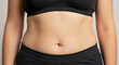 © Arra Vais - Adult torso showing subtle fat buildup with skin tone highlighted in cropped sportswear emphasizing the midsection. The torso displays natural body shape in a relaxed pose.