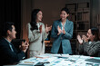 © Crystal - Group of business people clapping hands in late night office, celebrating achieving goals with teamwork and motivation