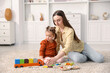 © New Africa - Mother and her daughter playing with toys on floor at home