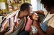 © Marko Geber - Parents tickling daughter on sofa at home