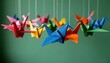 © CrazyJuke - Origami Cranes in Flight: Delicate origami cranes of various vibrant hues are suspended gracefully against a soft green backdrop, evoking a sense of tranquility and artistic beauty.