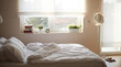 © Laura - Photograph of a bright and spacious bedroom with an unmade bed, window, plants, and natural morning light.