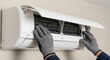 © Rabia - A gloved hand is shown servicing an air conditioning unit on a wall.
