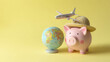 © Alex Alex - A pink piggy bank with a straw hat stands next to a globe on a yellow background, with a toy passenger plane flying over. Saving for a vacation and planning travel expenses.