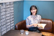 © amanaimages - カフェで本を読んでいる笑顔の女性