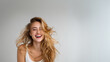 © overrust - bright studio portrait of laughing blonde woman with flowing hair, high key beauty portrait of joyful young woman on clean gray background, natural motion beauty portrait of smiling blonde woman