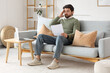 © Pixel-Shot - upset young man with order for his dismissal sitting on sofa at home