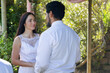 © Wavebreak Media - Couple exchanging vows beneath pergola in garden, woman wearing lace dress, man wearing white shirt