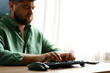 © fotofabrika - Man typing on keyboard while sitting at desk by window in a well-lit room